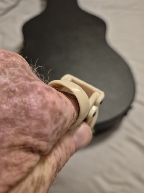 S.P.'s hand wearing the beige prosthetic held in front of his acoustic guitar body
